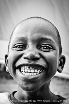 a black and white photo of a young boy with big eyes smiling for the camera