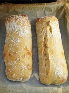 two loaves of bread sitting on top of a piece of wax paper