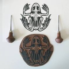 a wall mounted clock with an intricate design on it's face and two wooden spoons next to it