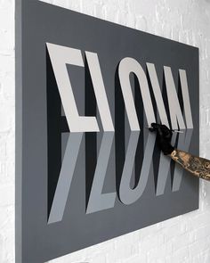 a man is cutting out the letters for a large wall art piece on a white brick wall