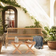 a wooden bench sitting next to a potted plant on top of a tiled floor