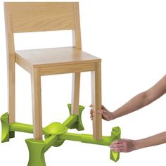 a child's wooden chair being held up by a green plastic handlebars