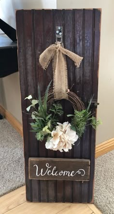 the welcome sign is decorated with flowers and greenery in front of a wooden door