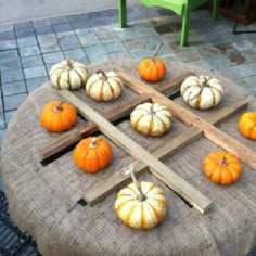 pumpkins and gourds are arranged on a round table with a cross in the middle