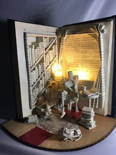 an open book with some books on it and a lamp in the corner next to it