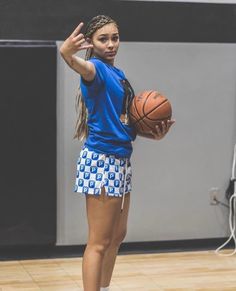 a young woman holding a basketball on top of a hard wood floor