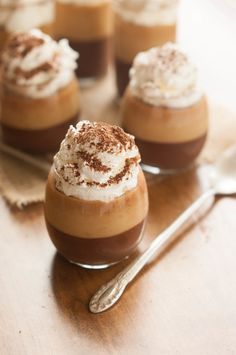 small desserts with whipped cream and chocolate on a wooden table next to silverware