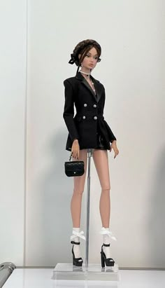 a barbie doll dressed in a black suit and high heeled shoes, holding a purse