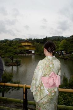 a woman in a kimono looking out over a lake