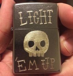 a lighter with a skull on it that says light em up in white ink and gold foil