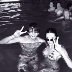 black and white photo of two people in the water with peace signs on their hands