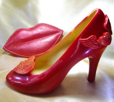 a pair of red high heeled shoes sitting on top of a white sheet