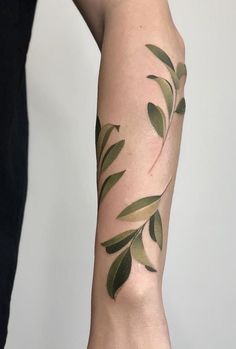 a woman's arm with green leaves on it