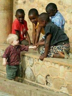 a group of young children standing next to each other on top of a stone wall