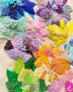 a bunch of different colored flowers sitting on top of a white cloth covered tablecloth