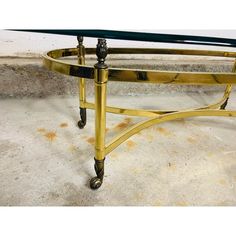 a glass and brass coffee table with wheels on the bottom, sitting in a room