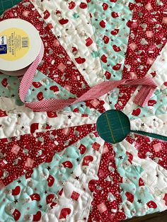 a close up of a quilted table topper with scissors and tape on it