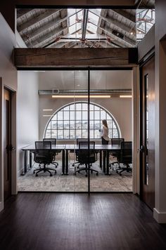 an empty conference room with glass walls and wooden floors is seen through the doorways