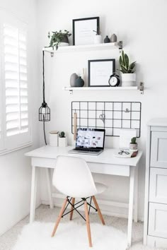 a white desk with a laptop computer on top of it next to a shelf filled with potted plants