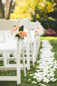 the aisle is lined with white chairs and pink roses on them for an outdoor ceremony