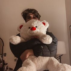 a man holding a large white teddy bear in his arms and wearing a black puffy jacket