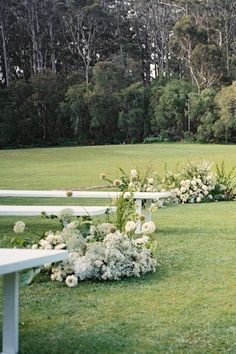 a row of white benches sitting on top of a lush green field