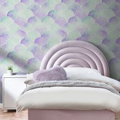 a bedroom with a bed, nightstand and wallpaper in pastel colors on the walls