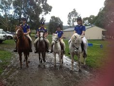 four people are riding horses in the mud