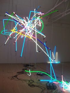 an art installation with various colored lights on the floor and wires hanging from it's ceiling