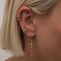 a woman with blonde hair is wearing gold ear cuffs and diamond hoops on her ears