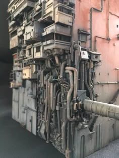 an industrial machine with many pipes and wires on it's side, in front of a pink wall