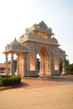 an ornate white building sitting on top of a cement ground next to a lush green field