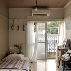 a bed sitting in a bedroom next to a window with curtains on top of it