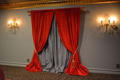 an empty room with red curtains and chandeliers on the wall, in front of a mirror