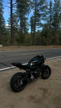 a motorcycle is parked on the side of the road in front of some pine trees