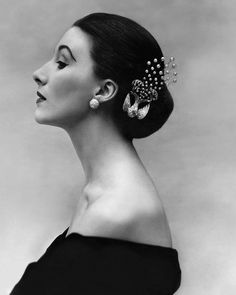 black and white photograph of a woman with earrings on her head, looking off to the side