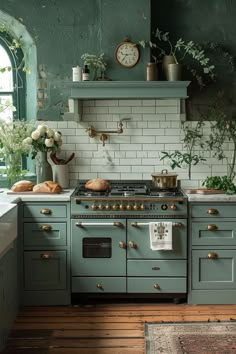 a kitchen with green painted cabinets and an old fashioned gas range in the center, surrounded by greenery