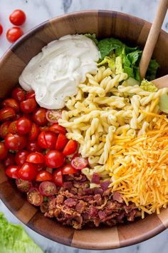 a wooden bowl filled with pasta salad ingredients