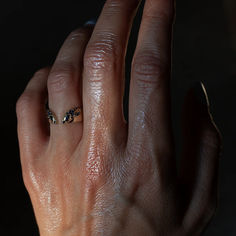 a person's hand with a ring on it, in the middle of their fingers