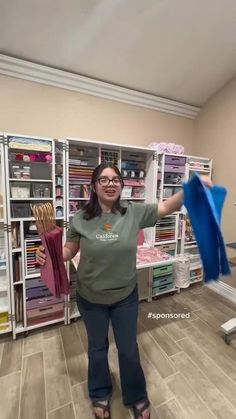 a woman holding up a blue umbrella in front of a bookcase filled with books