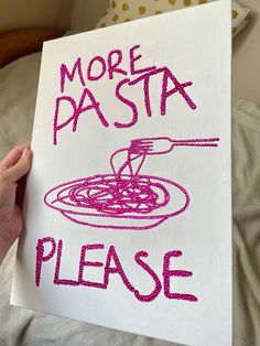 a hand holding up a sign that says more pasta please with pink thread on it