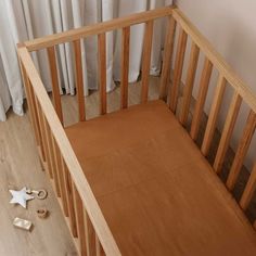 a baby crib with a blue sheet and wooden toys on the floor next to it