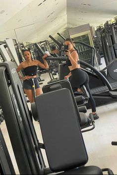 two women working out in the gym on machines