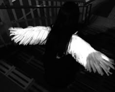 a woman with long black hair and white wings on her back is walking down stairs