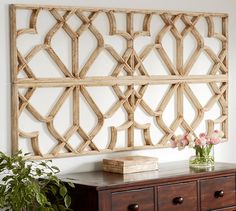 a wooden wall hanging over a dresser next to a potted plant on top of a table