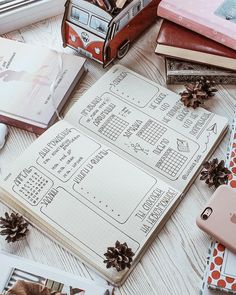 an open notebook sitting on top of a wooden table next to other books and decorations