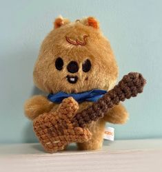 a brown teddy bear holding a crocheted guitar string