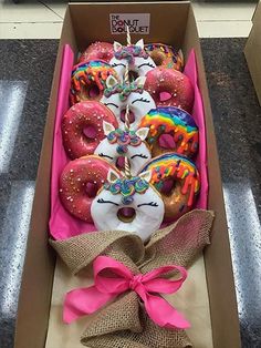 a box filled with lots of donuts covered in frosting and sprinkles