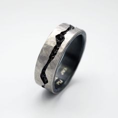 a wedding ring that has been made with silver and black diamonds