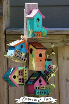 a birdhouse made out of cardboard and other things hanging from the side of a wooden fence